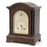 Embee, German oak bracket clock striking on four rods with barley twist columns and silvered dials