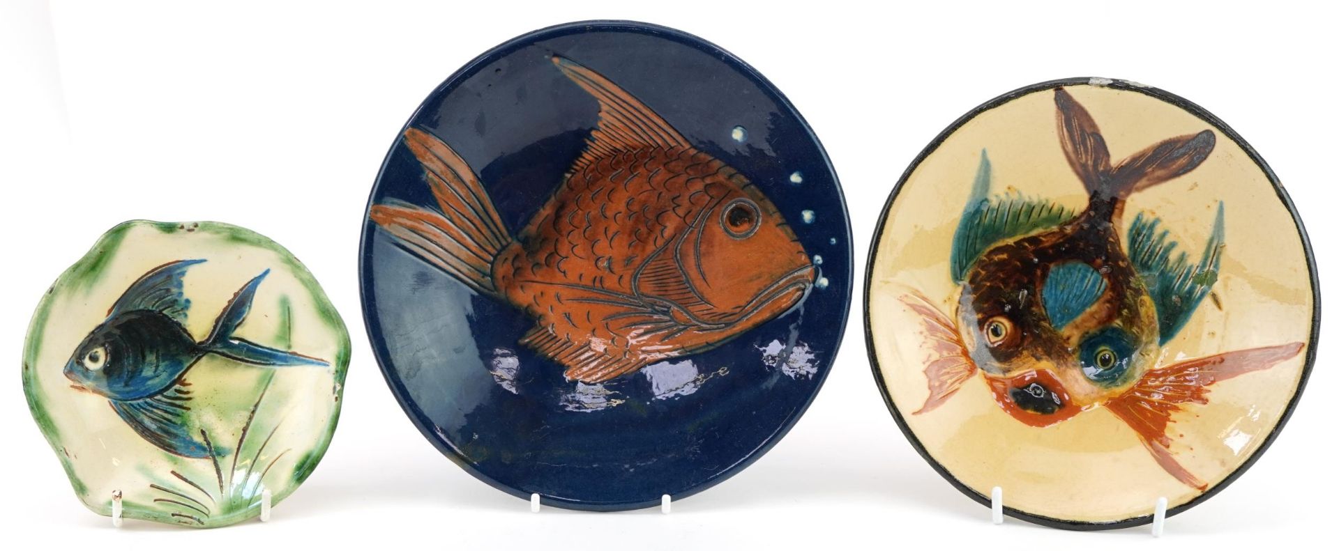 Three art pottery plates hand painted with stylised fish including one by Puigdemont, the largest