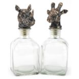 Pair of novelty glass decanters with rhinoceros and giraffe head stoppers, the largest 24cm high :