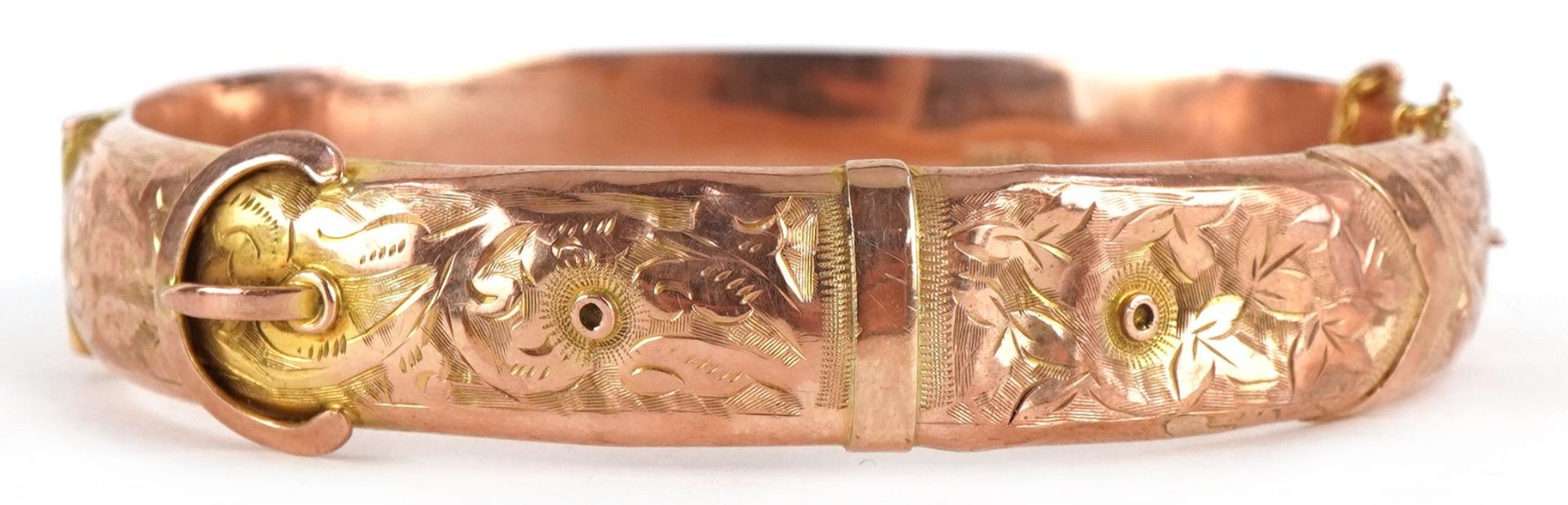 Edwardian 9ct rose gold buckle design hinged bangle engraved with flowers and foliage, 6.5cm wide,
