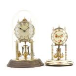 Two brass anniversary clocks housed under glass domes including a Kundo example, the largest 30cm