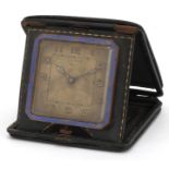 Art Deco brass and leather eight day travel clock with enamelled border and Arabic numerals, overall