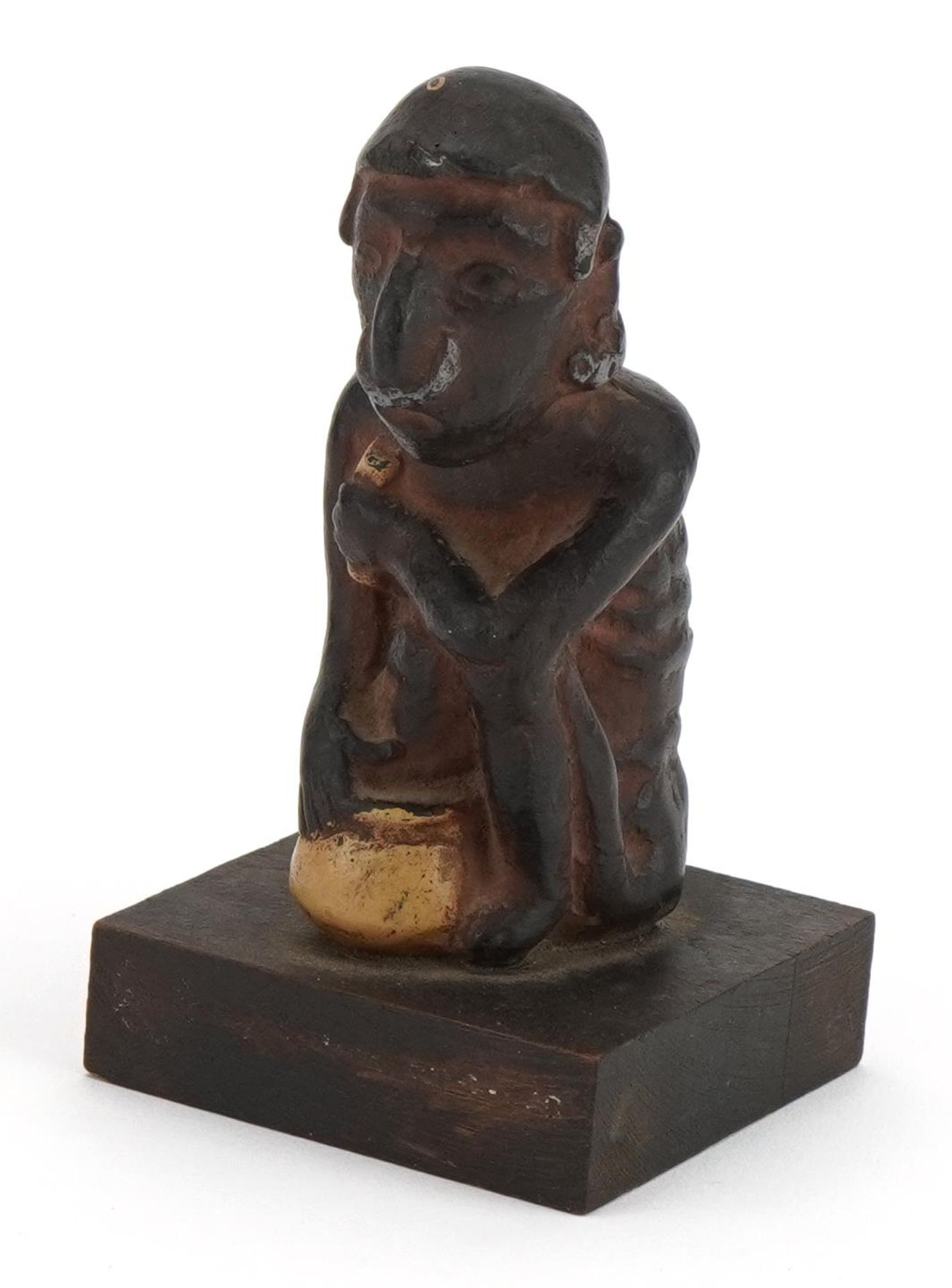 Tribal interest pottery figure of a crouched nude male raised on a wooden square block base, 13cm