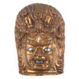 Antique Tibetan or Indian patinated bronze mask of Bhairava with silver eyes and teeth, 13.5cm