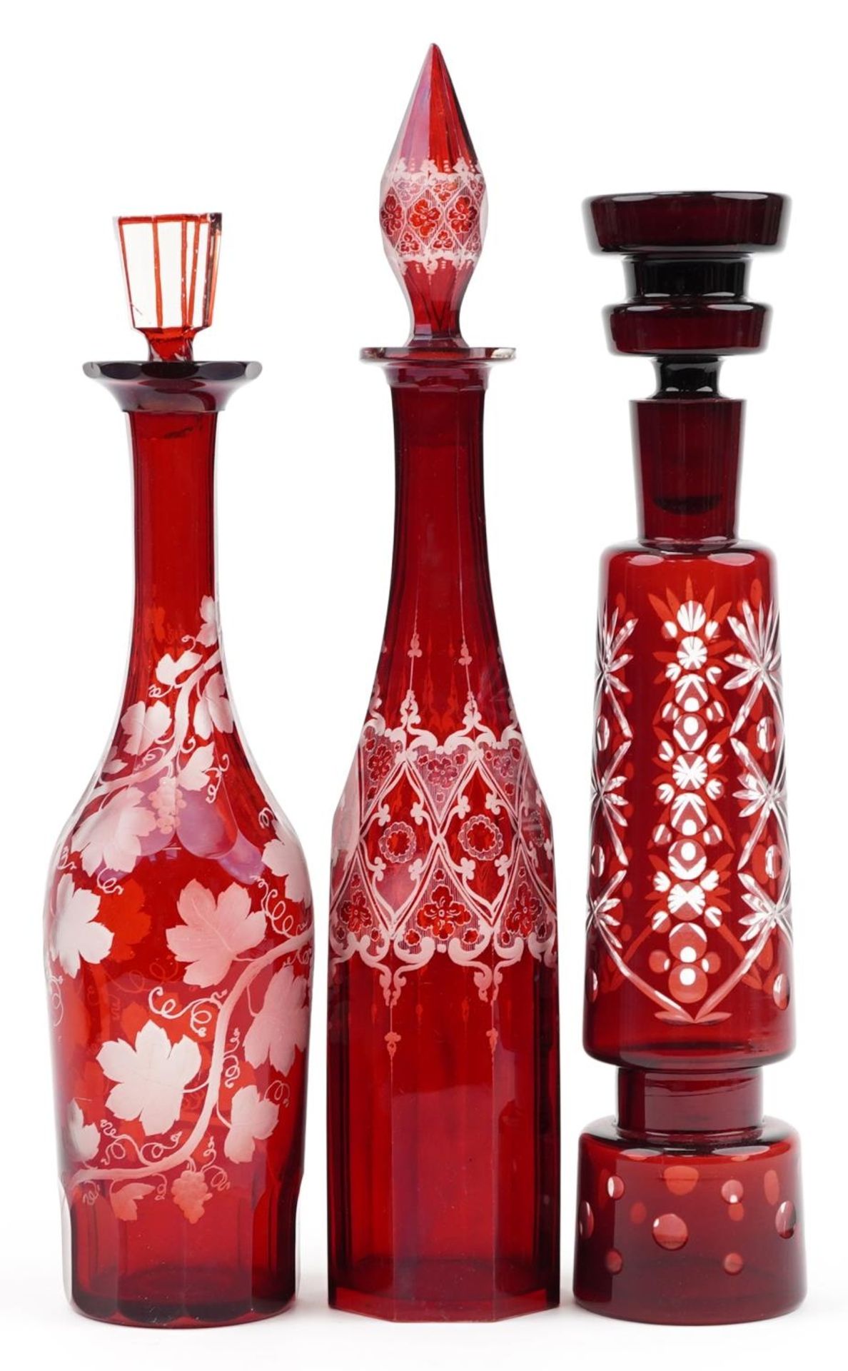 Three Bohemian ruby glass decanters with stoppers including one etched with grapevines, the