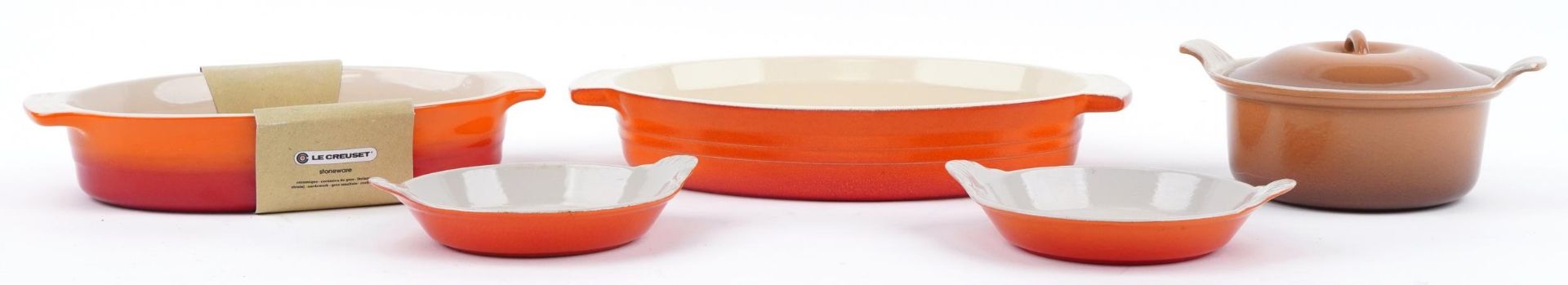 Le Creuset orange cooking dishes together with a Le Creuset crockpot with lid, the largest 35cm wide