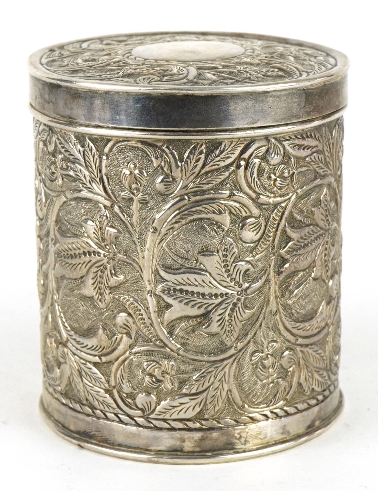 Anglo Indian cylindrical box and cover profusely embossed with flowers and foliage, engraved from