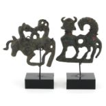 Two Persian Luristan patinated mythical animal bronzes including a handle, each raised on stands,
