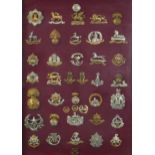 Military interest cap badges arranged in a glazed display including The Royal Sussex Regiment,