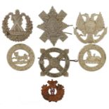 Seven military interest cap badges including Highland Regiments, Hampshire 1st Volunteer Battalion