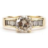 Unmarked gold diamond solitaire ring with baguette cut diamond set shoulders, the solitaire