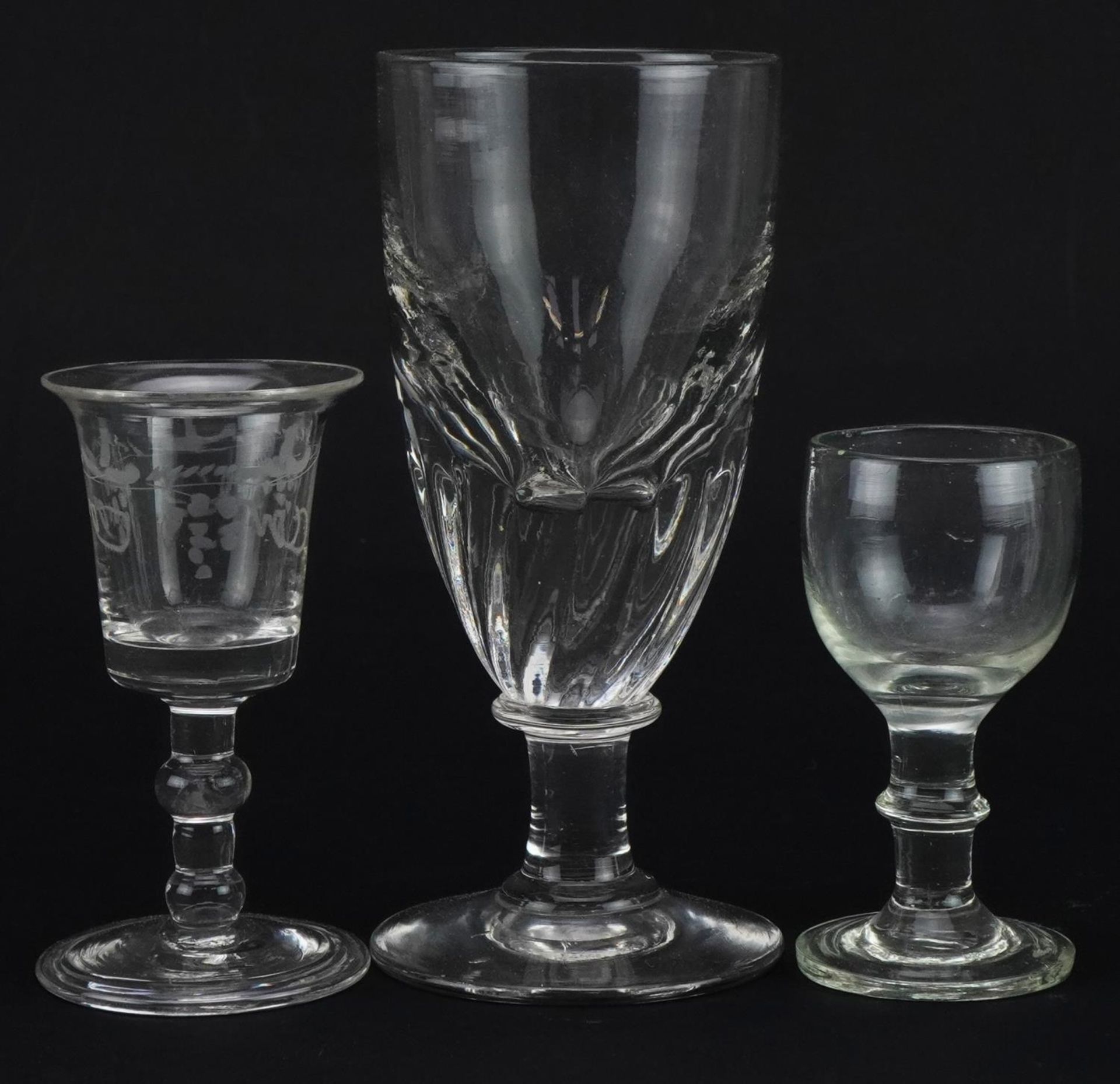 Three 18th century and later glasses including one with folded foot etched with berries, the largest
