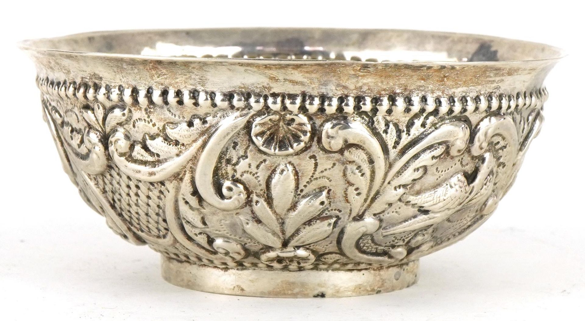 Asian circular silver footed bowl embossed with birds amongst flowers and foliage, possibly Thai,