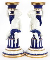 Mintons, pair of aesthetic porcelain Putti candlesticks, impressed marks and numbers to the bases,