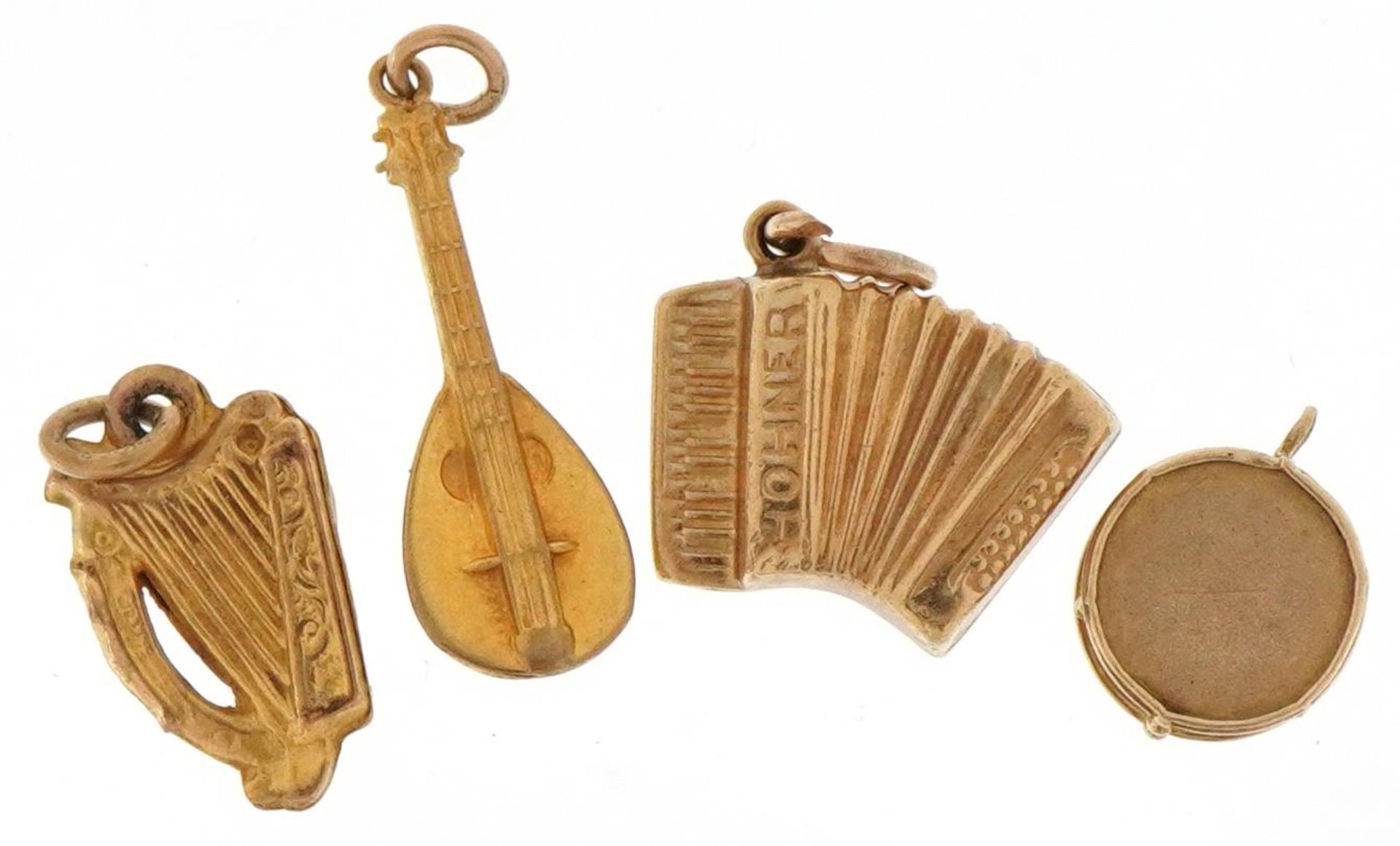 Four 9ct gold musical instrument charms comprising mandolin, accordion, drum and harp, the largest