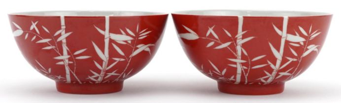 Pair of Chinese porcelain iron red ground bowls hand painted with bamboo grove, six figure character