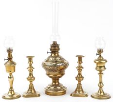 Three brass oil lamps and a pair of brass candlesticks with pushers, the largest overall 57cm high :
