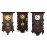 Three Vienna wall clocks with columns, each having painted chapter rings with Roman numerals, the