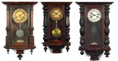 Three Vienna wall clocks with columns, each having painted chapter rings with Roman numerals, the