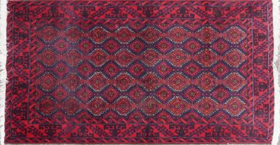Rectangular Persian red ground rug having an allover repeat design within a geometric border,