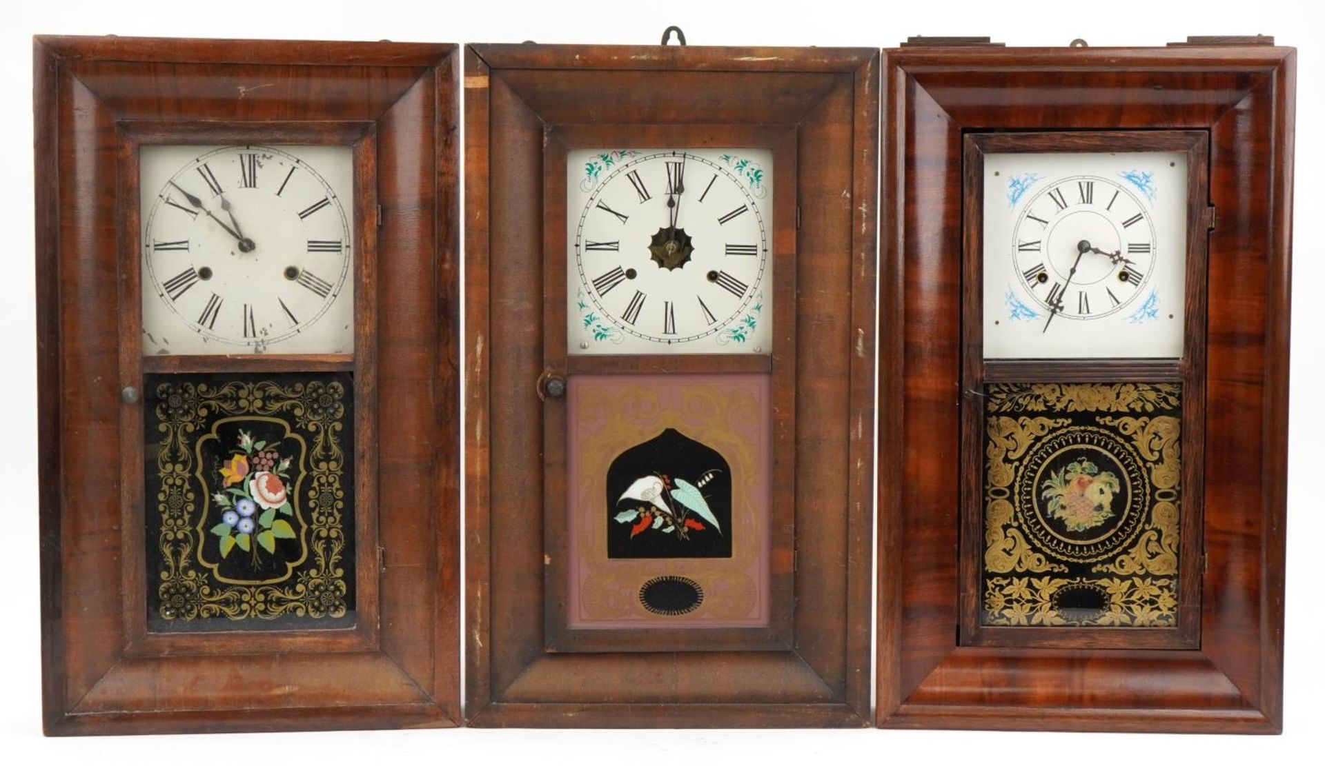 Three American walnut wall clocks with painted panels and dials having Roman numerals, each 66cm x