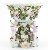 19th century German floral encrusted porcelain centrepiece surmounted with three Putti, 30cm high