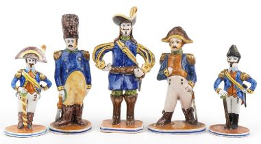 Set of five continental faience glazed figures of soldiers in uniform, the largest 28cm high : For