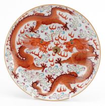 Chinese porcelain shallow dish hand painted in the famille rose palette in iron red with two dragons