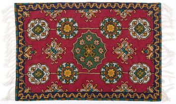 Rectangular Moroccan rug having an all over repeat flower head design onto a red ground, 88cm x 57cm