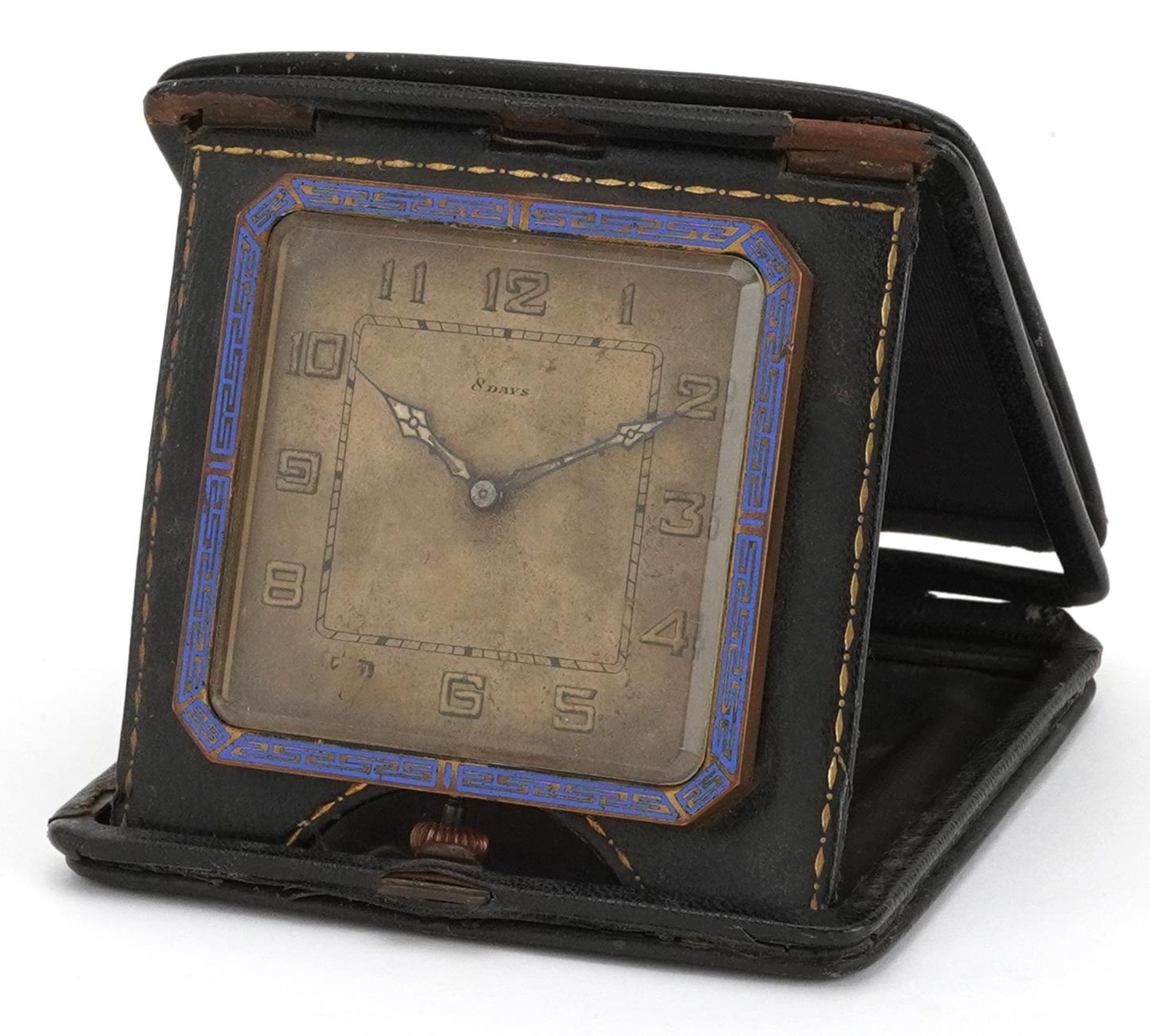 Art Deco brass and leather eight day travel clock with enamelled border and Arabic numerals, overall