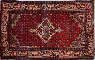 Rectangular Persian rug having a red ground central field with repeat design and central flower