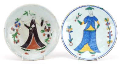 Two Iznik pottery shallow dishes hand painted with figures wearing traditional dress, the largest