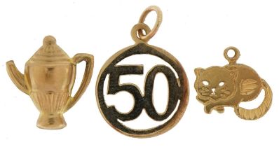 Three gold charms comprising 9ct gold 50, unmarked gold teapot, tests as 9ct gold, and 14ct gold