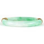 Chinese green jade bangle with unmarked gold mounts decorated in relief with dragons, 9.5cm in