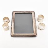 A SILVER FRONTED PICTURE FRAME TOGETHER WITH FOUR SILVER NAPKIN RINGS