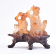 CARVED AGATE FIGURE OF TWO MONKEYS ON HARDWOOD STAND