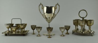 COLLECTION OF SILVER PLATE EGGCUPS & STANDS AND A TROPHY
