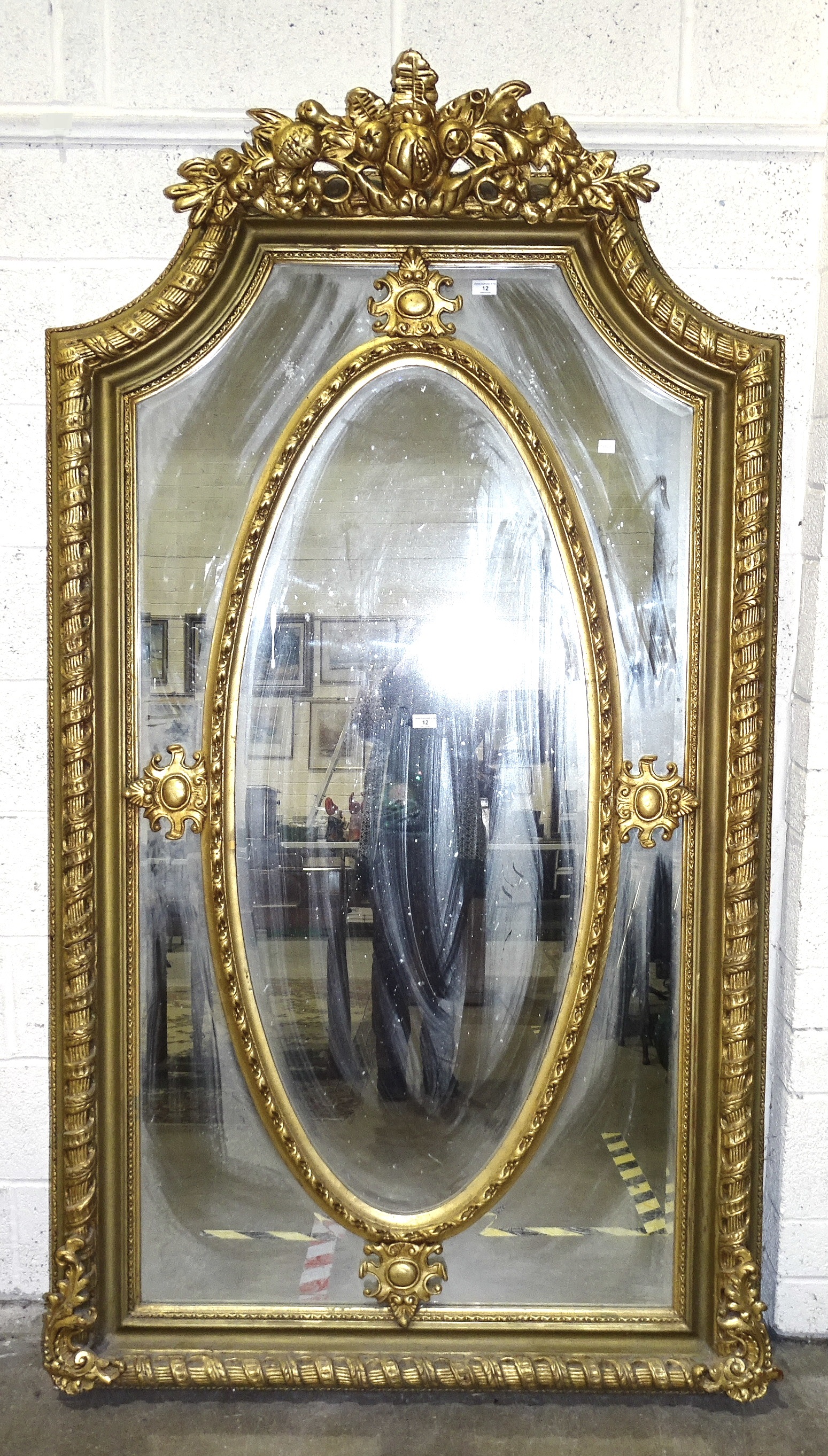 A large and impressive 20th century gilt gesso and wood mirror, the shaped top decorated with fruit,