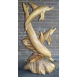 A carved wood sculpture of three dolphins, mother with two young, on naturalistic base, carved