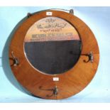 An Egyptian walnut advertising mirror and coat rack of circular form, the mirror painted with Arabic