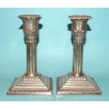 A pair of Edwardian silver candlesticks with leaf-capped reeded columns, on a stepped and leaf