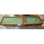 A Victorian walnut folding bagatelle board, with balls and one cue, 242cm open, 121cm x 61cm closed.