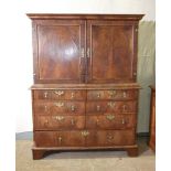 An early-18th century walnut press cupboard, the moulded cornice above two panelled doors, the lower