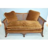 A 20th century mahogany Bergère caned settee with outswept arms, on blind-fret frame and carved