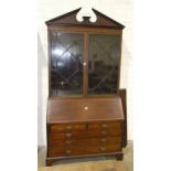A large mahogany cross-banded bureau/bookcase, the pediment above a pair of astragal-glazed doors,