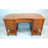 An Edwardian walnut knee-hole desk, the top with canted rear corners above an arrangement of seven