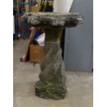 A cast concrete bird bath supported on four inter-twined dolphins, 53cm diameter, 80cm high.