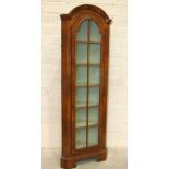 A walnut narrow corner display cabinet, the arched cornice above a single astragal-glazed door, on