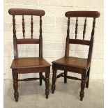 A pair of 19th century oak hall chairs, each with turned spindle back and solid seat, on tapered