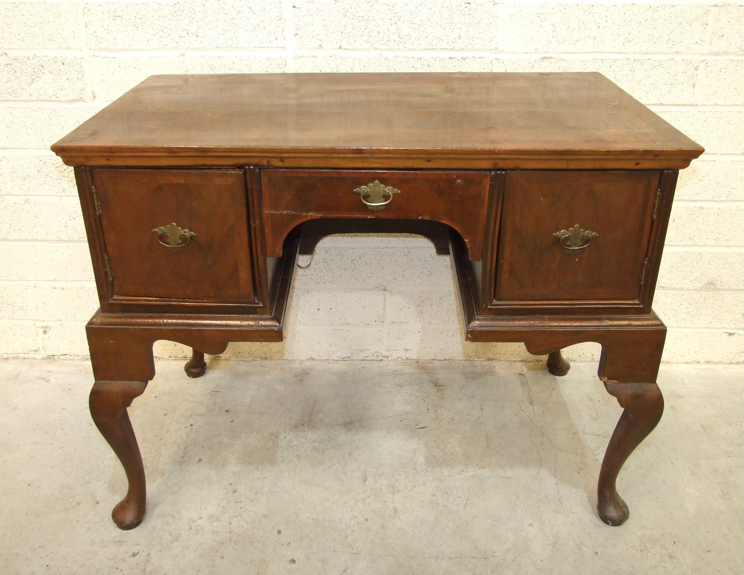 An 18th century walnut feather-banded lowboy, having a central drawer and two small cupboards, on